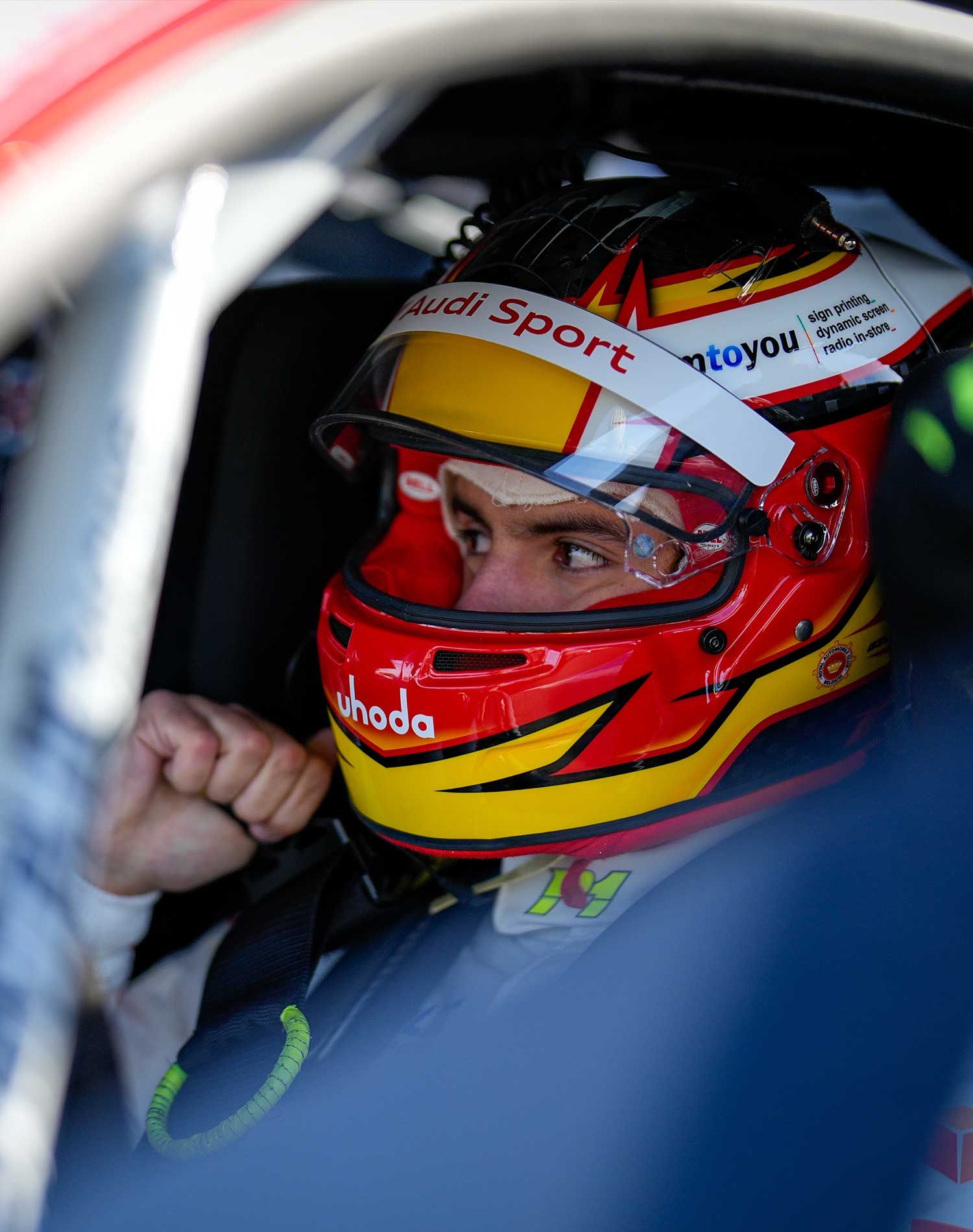 Racing driver in a red and yellow helmet sitting in the cockpit