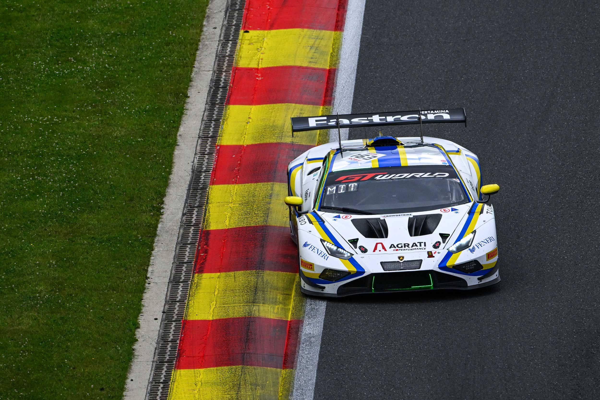 GT car running over red and yellow kerbs, seen from above